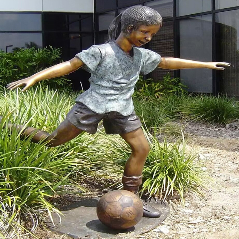 Escultura de niña de bronce jugando al fútbol