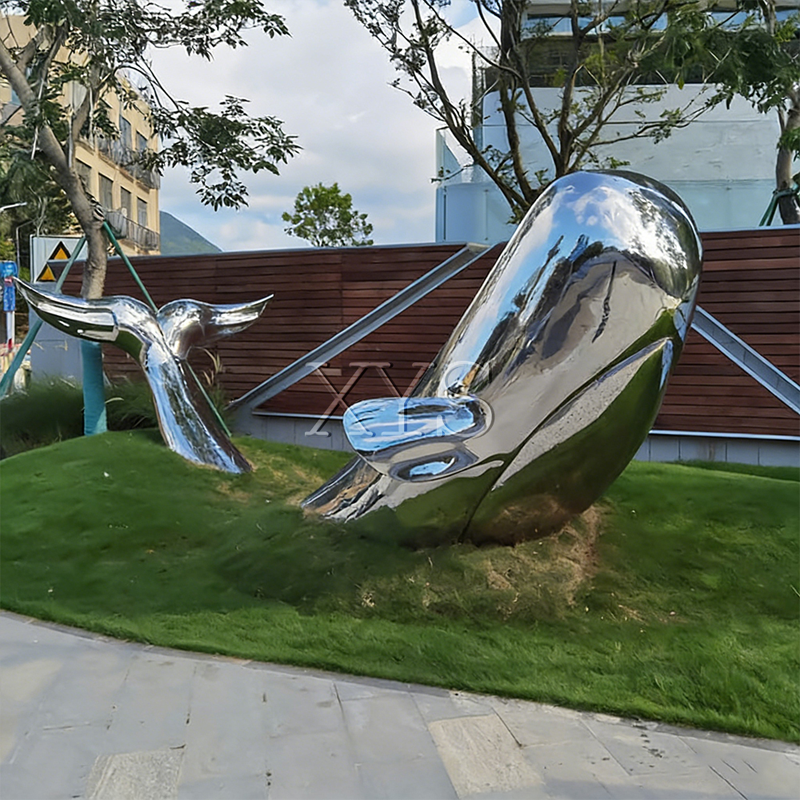 Escultura de ballena saltando de espejo de brecha