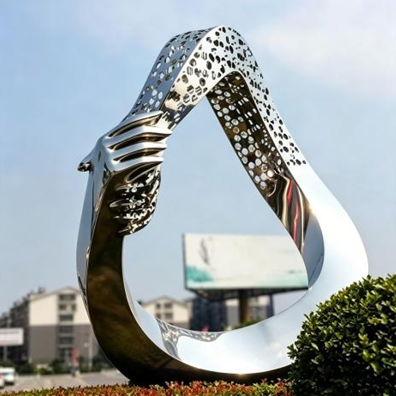 Manos abrazando escultura de acero inoxidable hueca en forma de gota de agua