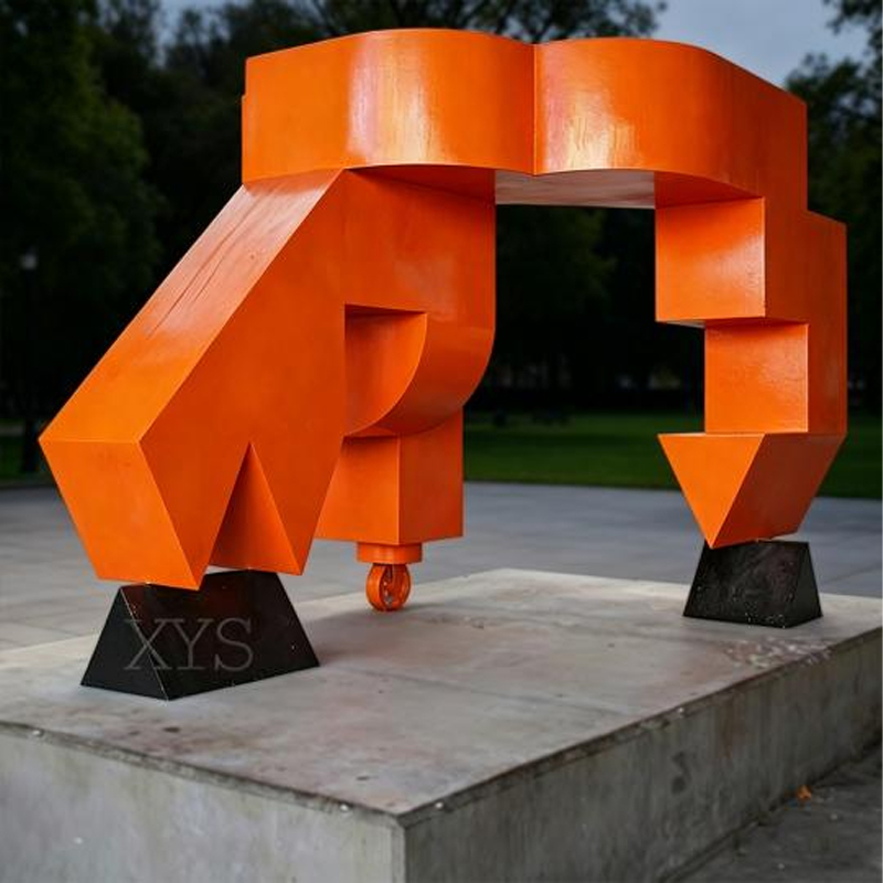 Escultura de acero inoxidable con composición de letras abstractas geométricas